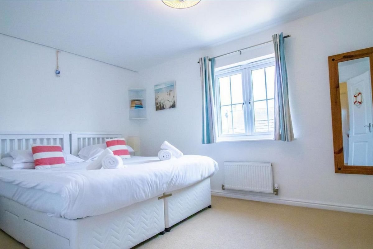 Master bedroom at Beachside Cottage with a king-size bed, white linen and red striped cushions