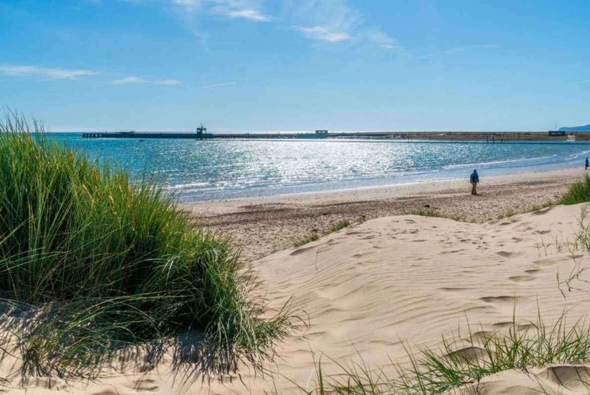 View through the dune grass to the blue sea and beach at Camber Sands