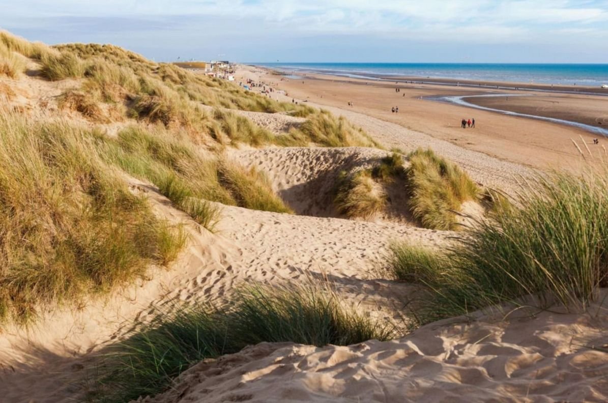 Golden sand dunes with marram grass at Camber Sands, East Sussex, looking down to the beach and sea